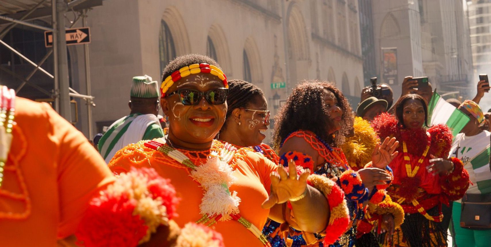 Women in bright orange outfits celebrating at a parade